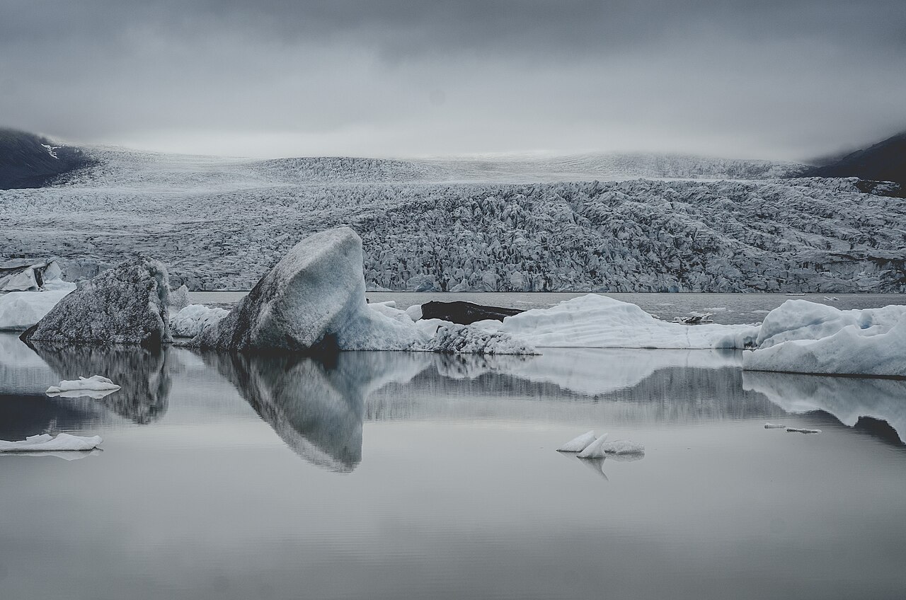 Icebergs reflected in Fjallsárlón with the glacier rising behind the lagoon